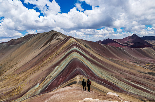 Tourists couple stand and look afar at Rainbow Mountains, Cusco, Peru.