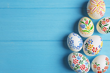 Beautiful Easter eggs with floral ornament on blue wooden background