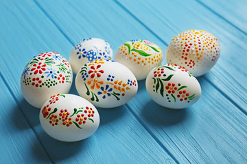 Beautiful Easter eggs with floral ornament on blue wooden background