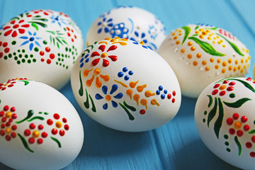Beautiful Easter eggs with floral ornament on blue wooden background, closeup