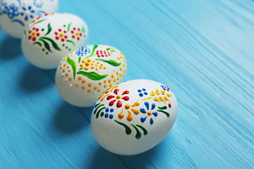 Beautiful Easter eggs with floral ornament on blue wooden background