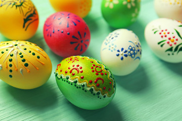 Beautiful Easter eggs with floral ornament on green wooden background, closeup