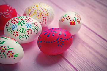 Beautiful Easter eggs with floral ornament on pink wooden background, closeup