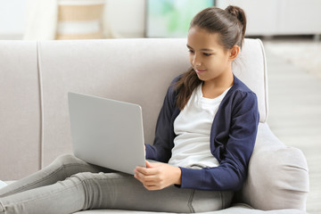 Cute girl sitting on sofa with laptop