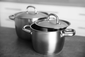 Kitchenware concept. Stainless saucepans on grey kitchen table, closeup