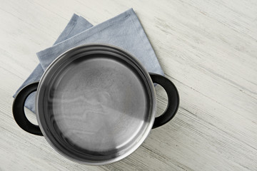 Stainless saucepan and napkin on white wooden table © Africa Studio