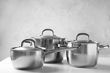 Kitchenware concept. Stainless saucepans on table and blue textured background