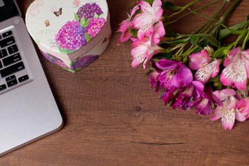 Laptop on wood floor with flowers. alstroemeria