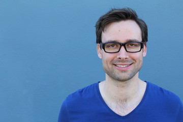 Natural good looking young man smiling with space for copy over blue background 