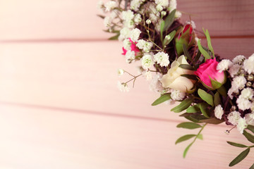 Floral wreath with beautiful flowers on light wooden background