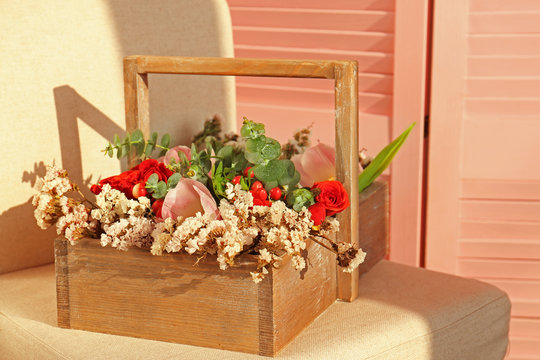 Square wooden box with beautiful flowers on a light textile chair