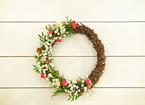 Floral wreath with beautiful flowers on light plank background