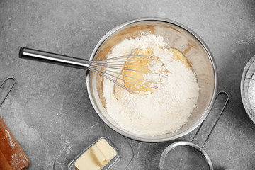 Bowl with flour, dough and whisk on kitchen table