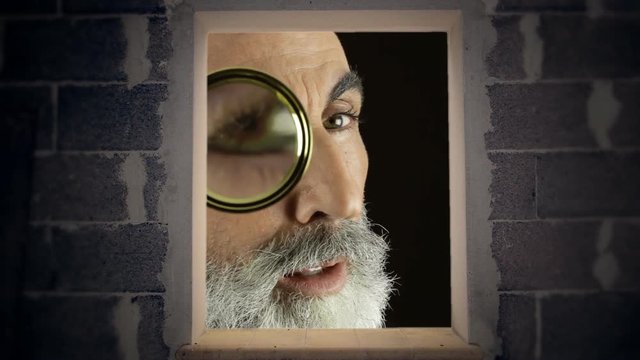 A giant man looking inside a bare room with a magnifying lens (a detective / private eye), finding what he was searching for.
