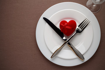Valentines day table setting with red heart and cutlery on a plate.