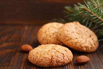 Almond cookie on a brown wooden background, the branches of spruce