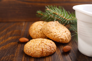 Almond cookie on a brown wooden background, the branches of spruce