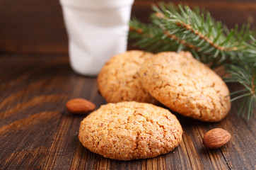 Almond cookie on a brown wooden background, the branches of spruce