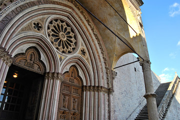 Fototapeta na wymiar Decorated portals and gothic rose window of the Basilica Inferiore di San Francesco, lower church of the Papal Basilica of Assisi, Italy