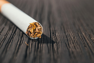 cigarette left on the brown wooden table, close up with copy space