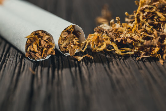 homemade cigarettes and tobacco on the brown wooden table, close up with copy space