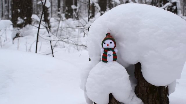 Forest in winter. Snowman standing on a tree stump