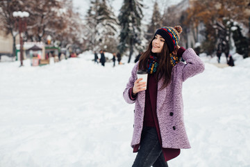 Fototapeta na wymiar Girl walking the winter street and drinking coffee