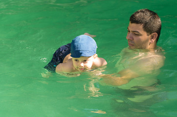 Young father with little son in pool