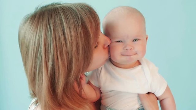 Mother kissing a baby on the cheek kindly in slow motion.