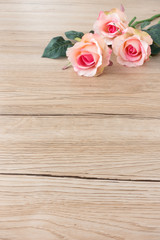Three beautiful pink roses in top right corner on brown wooden background with lots of copy space. Selective focus on rose in the front.
