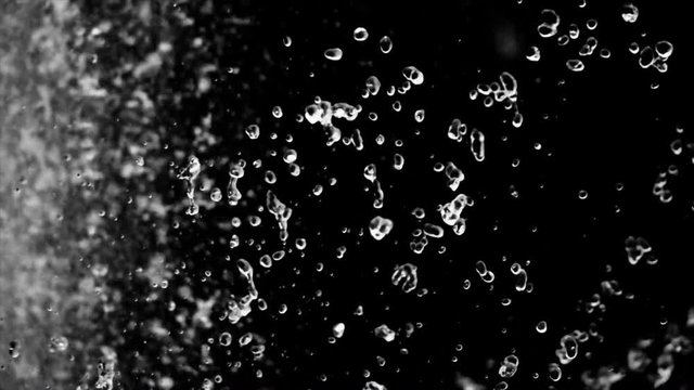 Beautiful drops of water fly slow motion on dark background