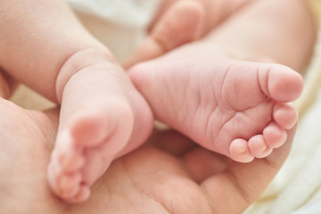 Obraz na płótnie Canvas Newborn baby feet in dad's hand