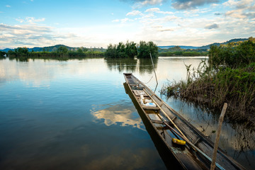 wooden rowboat in the calm water of lake at beautiful sunset