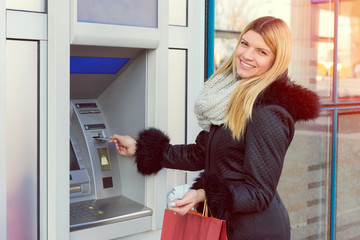 Young woman withdrawing money from credit card at ATM cash machine