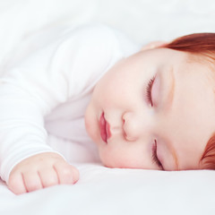 beautiful redhead infant baby sleeping in bed