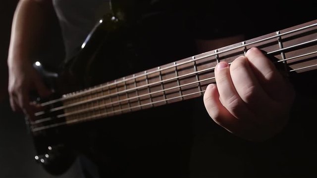 Closeup. Grief and string electric bass guitar. Slow motion