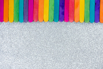 Colorful Popsicle sticks and white silver glitter texture background