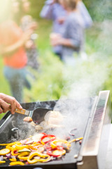 Close-up on hands grilling meat and vegetables on a plancha.