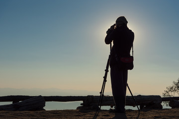 Silhouette of photographer taking photos in the mountains. Filter effect style