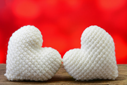 Two white heart on wooden table and red background