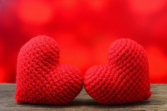 Two red heart on wooden table and red background