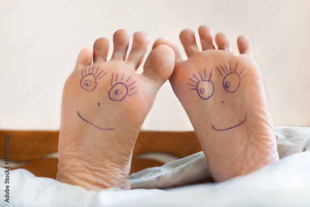 Wall mural Pair of female feet with smiling faces on it.