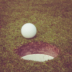 golf ball on lip of cup. Golf ball on green grass in golf course