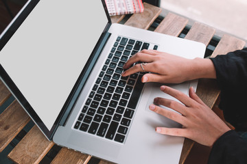 Hands of young woman typing on a laptop keyboard on a stone table. Close up. Isolated screen.