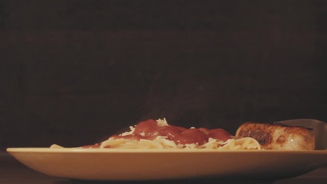 Hot spaghetti on a plate with tomato sause and sausage