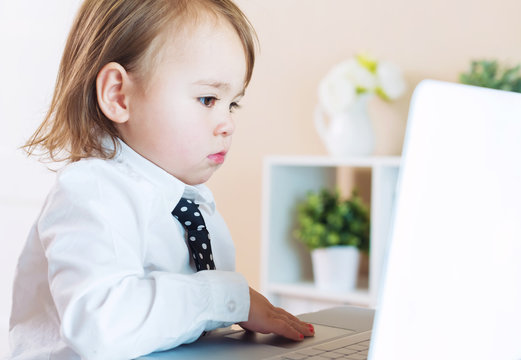 Serious toddler girl using her laptop