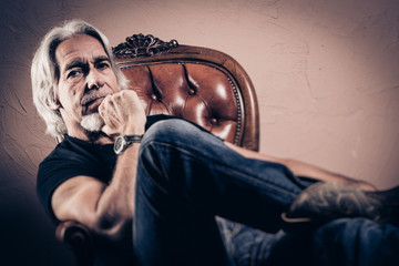 Senior Man Sitting In Armchair, Studio Portrait
