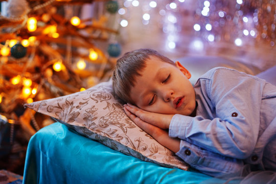 Little Cute Blond Boy Sleeping Under Christmas Tree And Dreaming