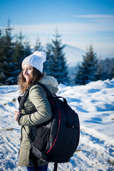 Girl backpacker walking in winter mountain forest