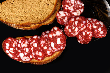Smoked sausage and bread on a black background